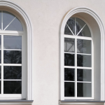 Arched windows with reflective glass in a beige building facade, showcasing classic architectural design